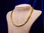 Gold Cuabn link chain necklace on a mannequin bust against a dark background