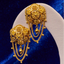 Gold Filigree stud earrings on a white stand against a blue background