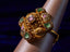 Gold ring with gemstones on a grey display stand against a dark background