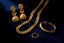 Gold jewelry including earrings, necklace, and rings on a dark blue background