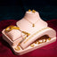 Collection of 22k gold jewelry by Virani Jewelers on a pink display stand against a dark background