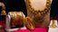 22K Gold temple jewelry including necklaces and bangles on a red and beige background