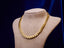 Gold Cuban link chain necklace on a mannequin bust against a dark background