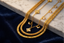 A set of gold-toned jewelry chains and delicate charms with small pearl-like beads, arranged on a white marble slab over dark navy velvet fabric.