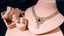 Diamond bridal jewelry set by Virani Jewelers including necklace, earrings, and bangles on a soft pink stand against a dark blue background