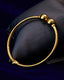 Gold beaded bangle for kids on a dark blue fabric background