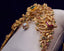 Gold vanki arm bracelet with gemstones on a white cushion against a dark background