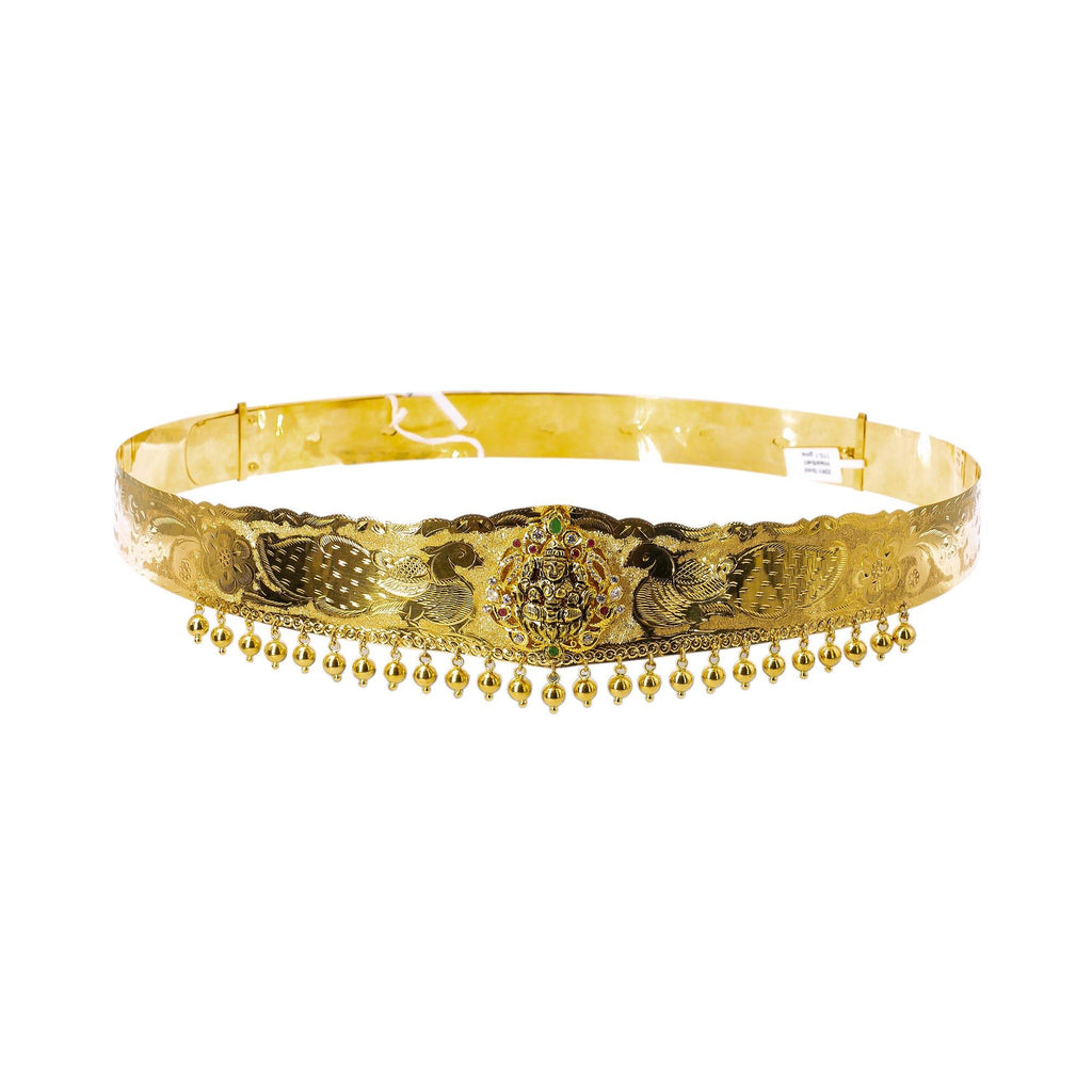 A picture featuring a 22K waist belt from Virani Jewelers that has a raised image of Laxmi along with laser-etched peacock details and hanging gold balls. | Add movement and luxury to your most festive looks with Vaddanam waist belts that will transform ...