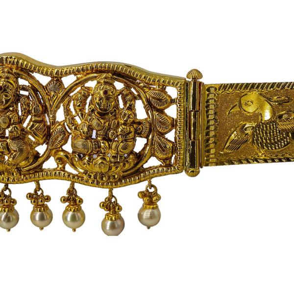A side view of a 22K waist belt with an antique finish from Virani Jewelers featuring hanging pearls that sit under the images of Laxmi. | Add movement and luxury to your most festive looks with Vaddanam waist belts that will transform ...